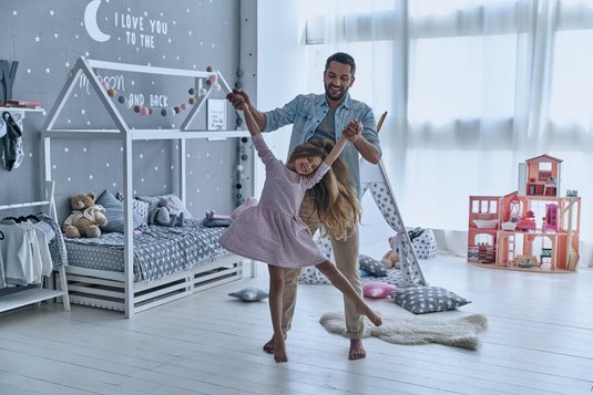 Vater und Tochter tanzen glücklich im neuen Haus.